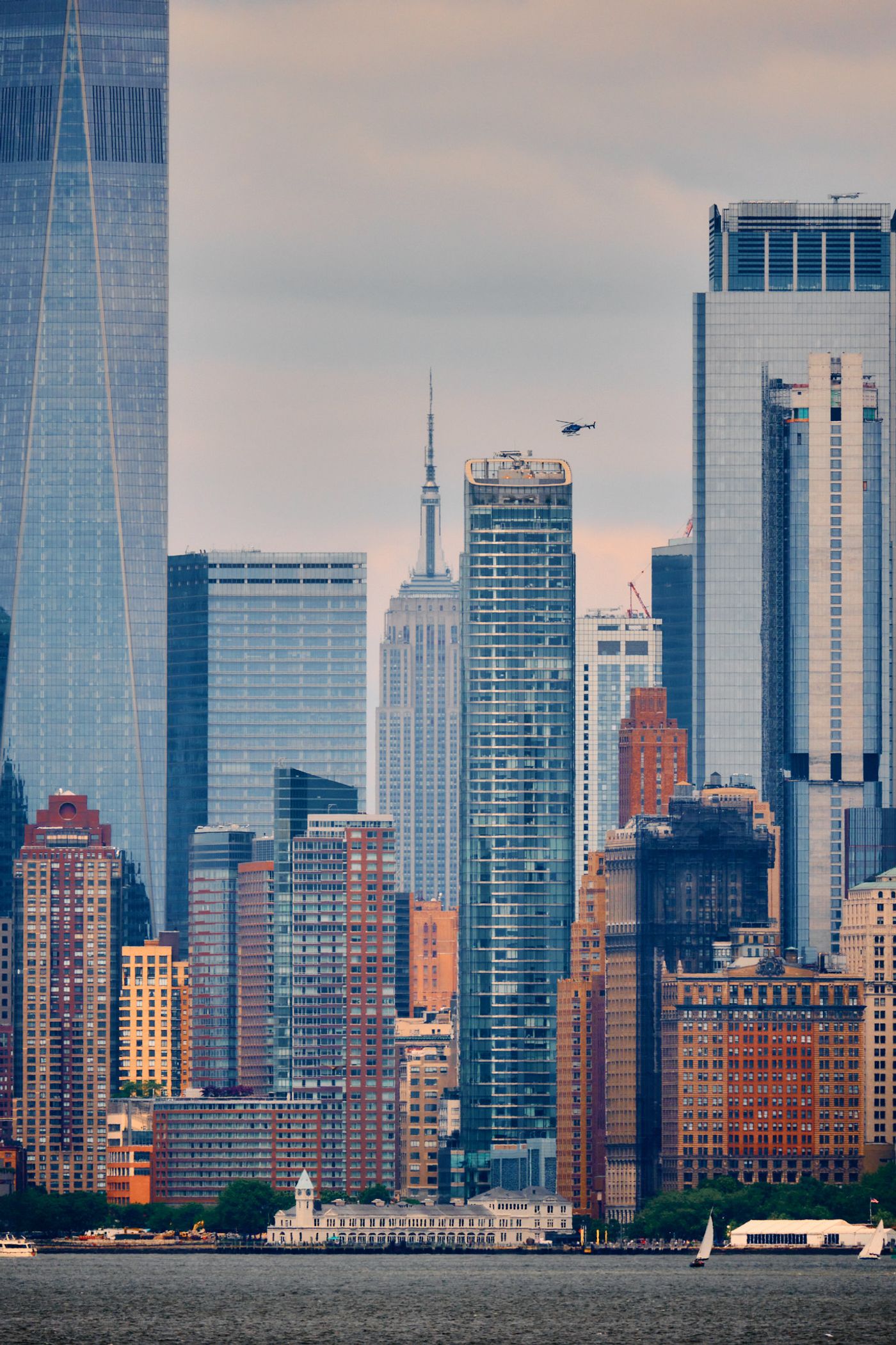 The image captures a cityscape with a mix of modern and older buildings, including the One World Trade Center and the Empire State Building. The sky i