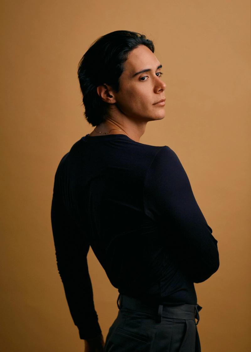 Three-quarter portrait of a male model in dark clothing and warm studio light