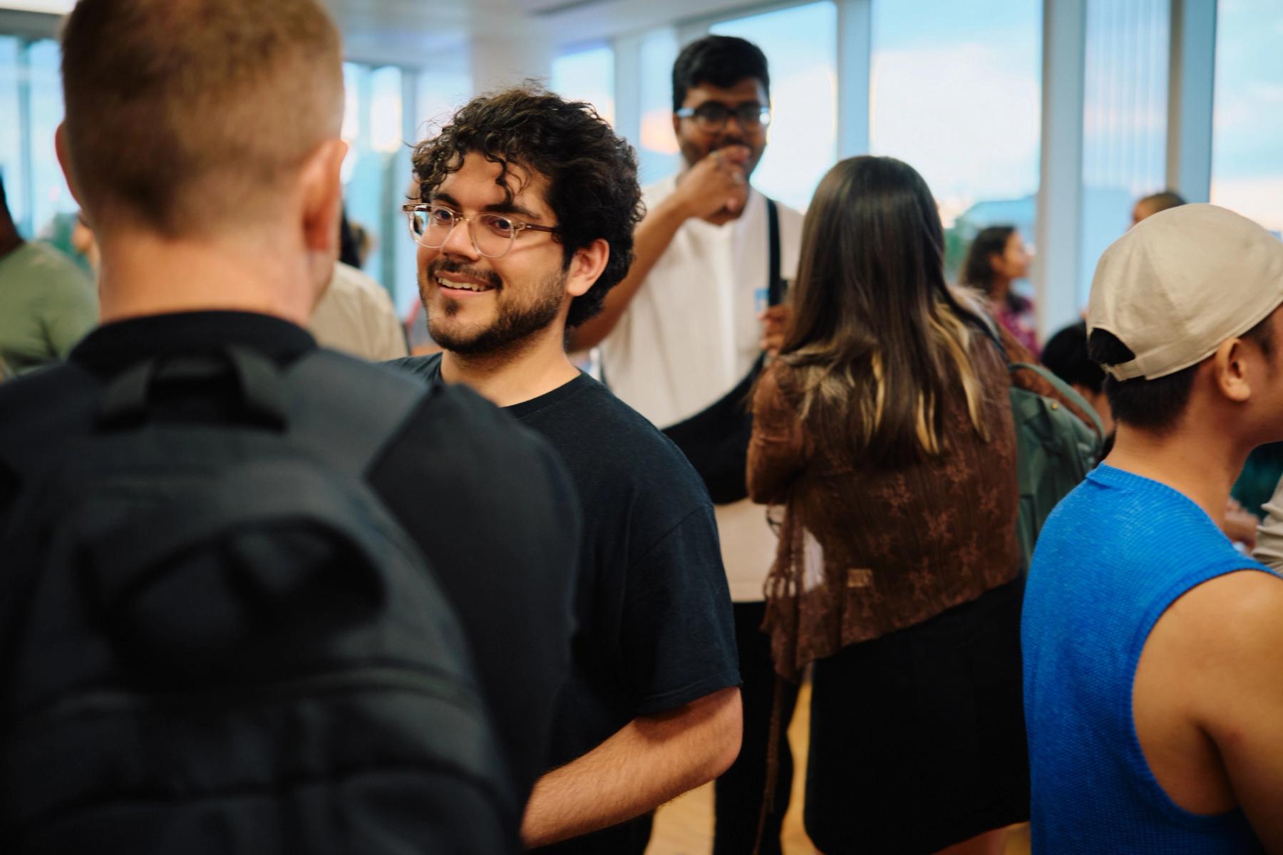 Access VFX community event 2026, young man with curly hair and glasses smiling while talking in a sunlit room