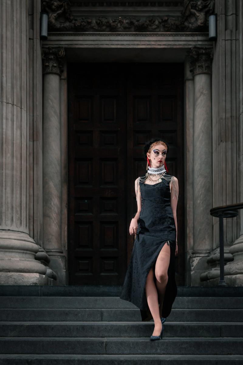 Woman in a black dress standing in a grand architectural hallway