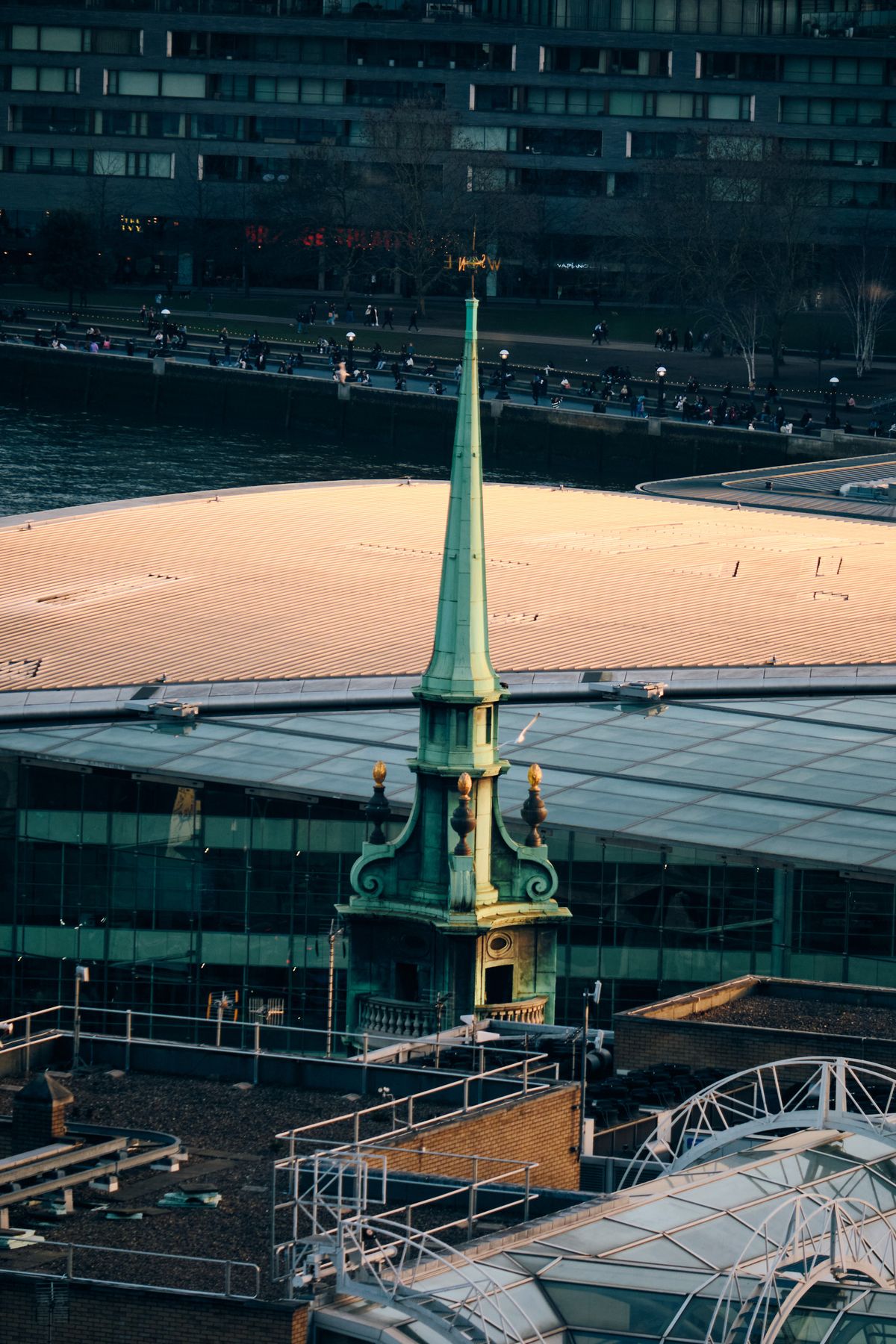 Modern glass high-rise building corner with turquoise and mauve tinted curtain wall and black aluminium framing against deep blue sky