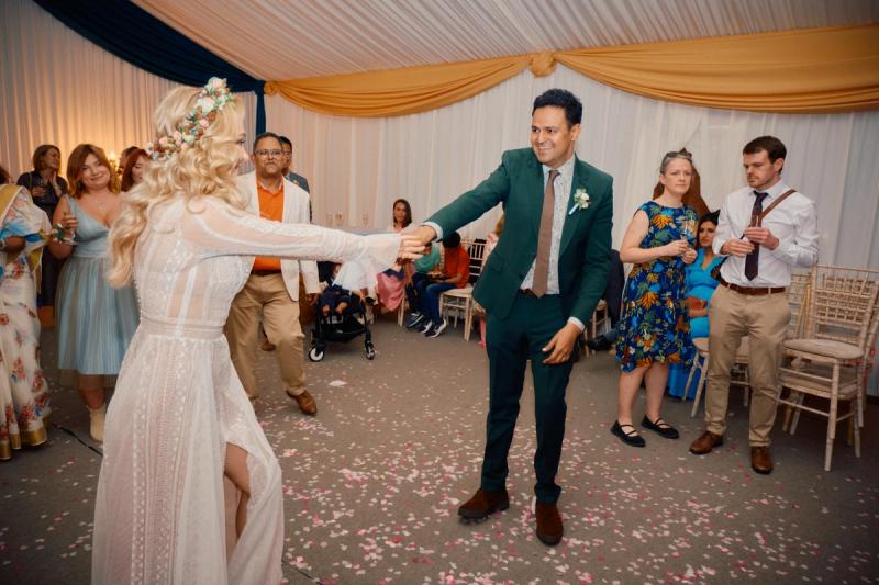 Bride and groom dancing under draped lights at the wedding reception