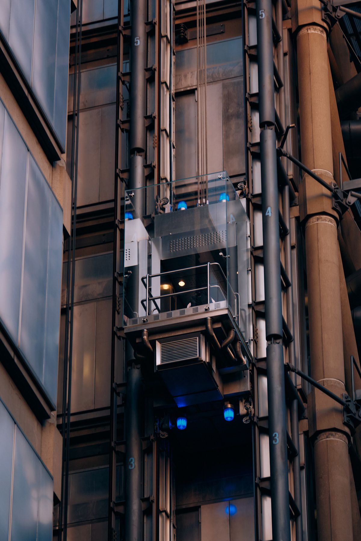 Modern urban alleyway at dusk with glass building facade, blue accent lighting and businessman on outdoor platform, contemporary commercial architecture