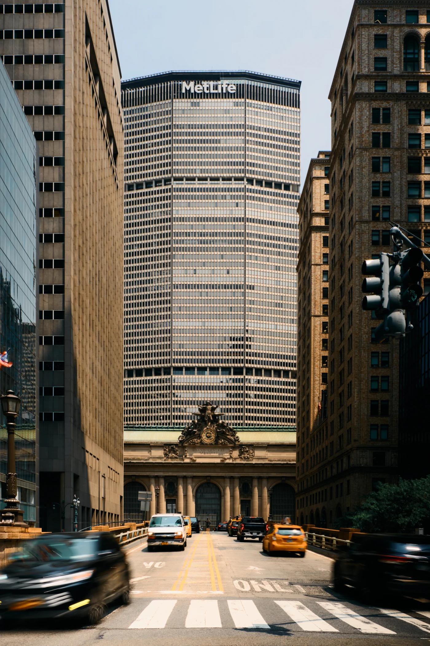 A bustling city street with tall buildings, cars, and a traffic light.