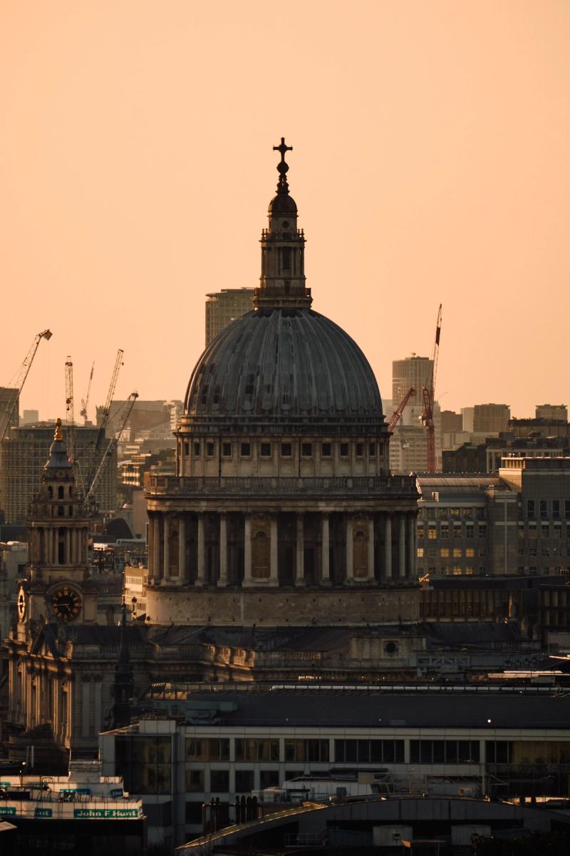 St. Paul's Cathedral London at golden hour sunset, iconic Baroque dome with Corinthian columns and modern city skyline