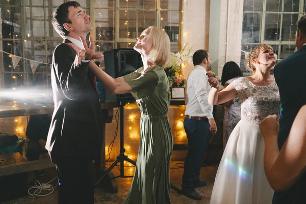 Dancers at the reception at night — groom and woman in green laughing, bride smiling beside them