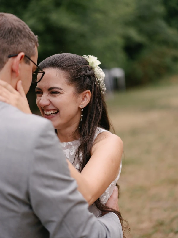 Bride laughing with happy expression while groom spins her around at outdoor garden wedding.