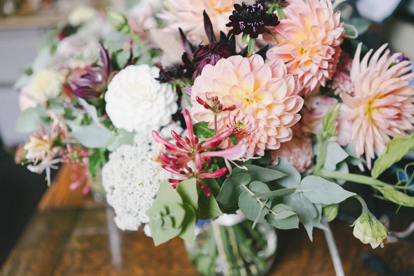Bridal bouquet close-up — peach dahlias, white roses, deep burgundy blooms and eucalyptus