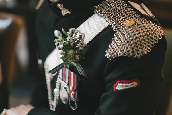 Groom in ceremonial military uniform holds the bridal bouquet detail with white gloves