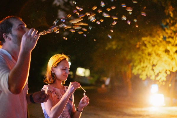 Couple dancing joyfully at wedding reception with sparkler backdrop — golden light, intimate dance, festive celebration moment.
