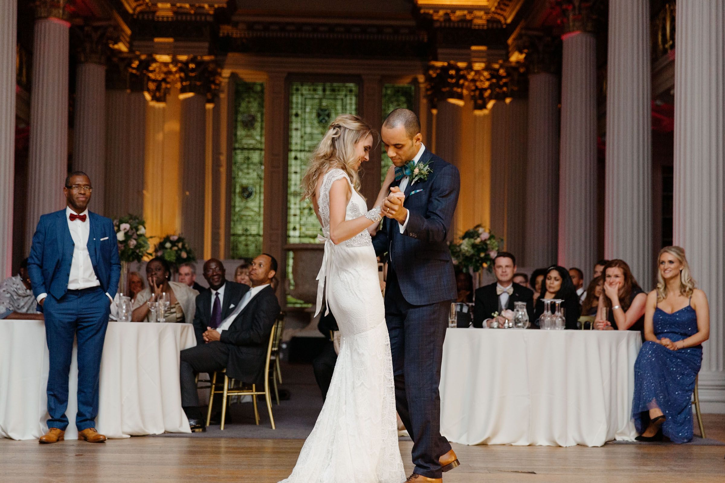 Bride and groom share their first dance at The Signet Library, surrounded by seated wedding guests.