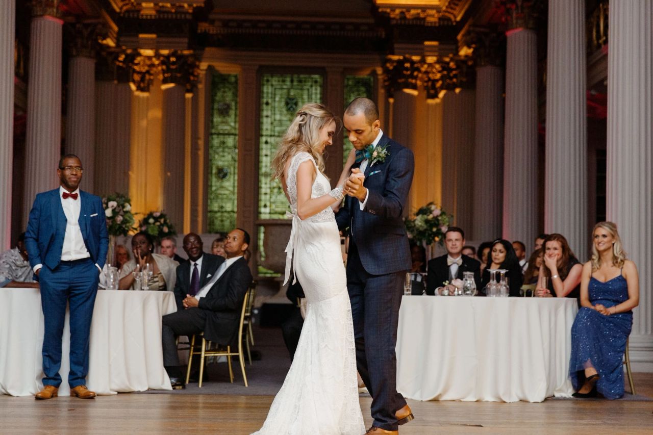 Bride and groom share their first dance at The Signet Library, surrounded by seated wedding guests.