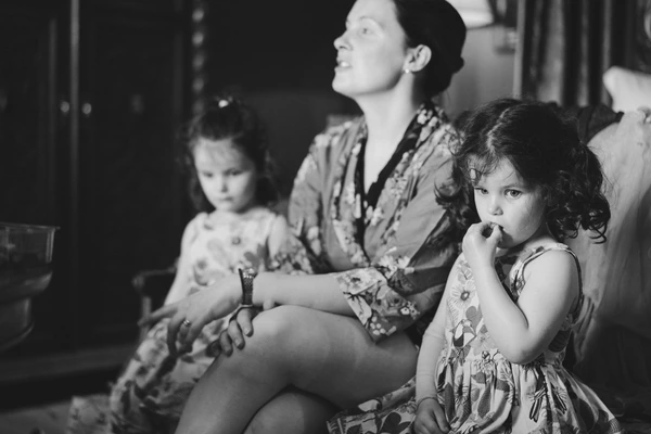 Mother with two daughters sitting together, all looking ahead — black-and-white, intimate family moment