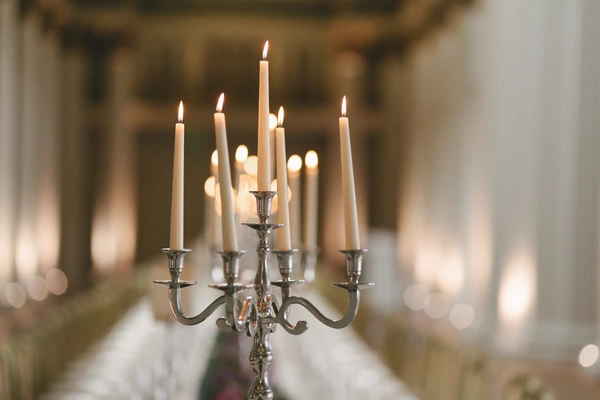 Silver candelabra with burning candles in the church, blurred ecclesiastical interior behind