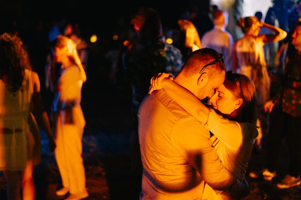 Groom and bride dancing at wedding in colorful tent venue — ambient gold lighting, elegant celebration moment.