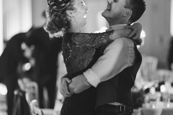 Groom embraces the bride in a joyful moment at the wedding reception — black-and-white
