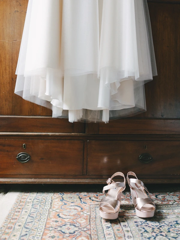 White tulle and silk bridal skirt ruffles, platform wedding shoes on an antique rug