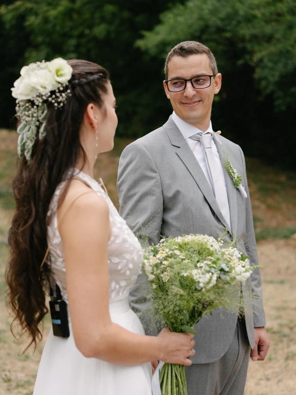 Bride and groom smiling together with white daisy bouquet during outdoor garden wedding portrait.