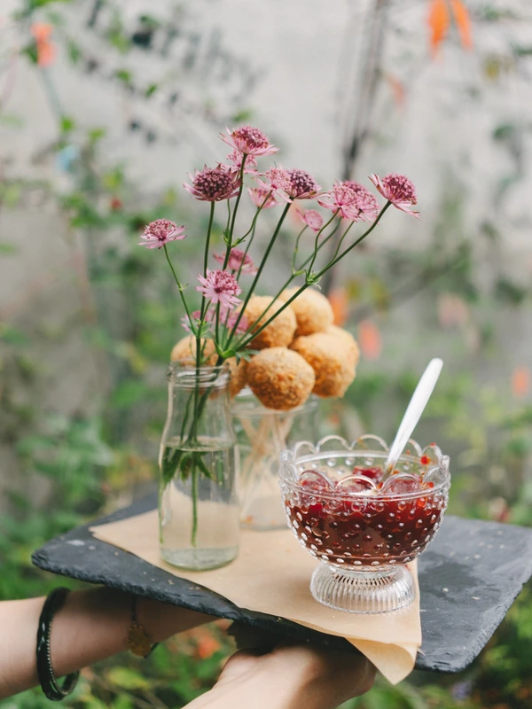 Hand-held black slate with floral decoration — pink astilbe flowers in a vase, spiced jam