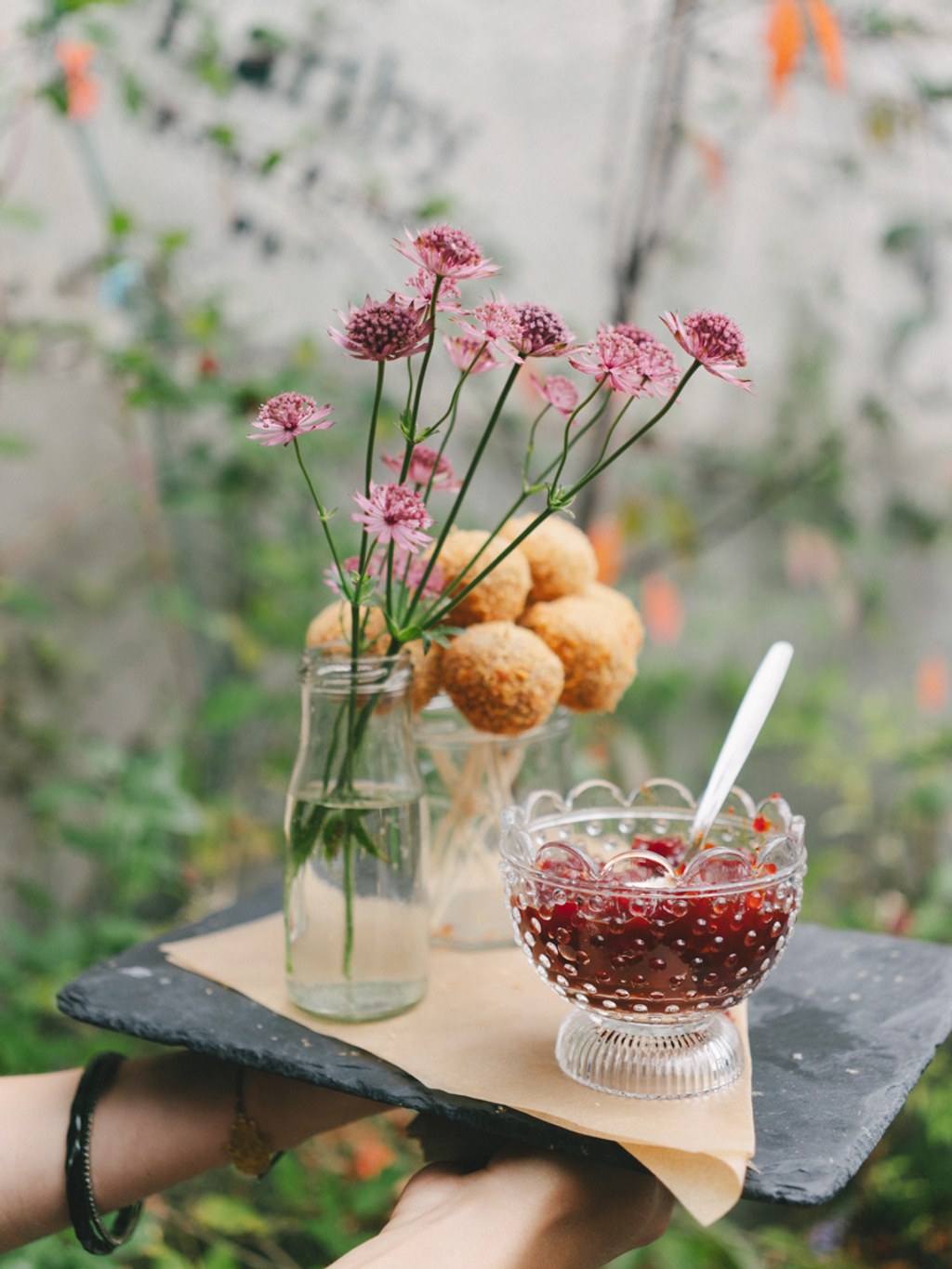 Hand-held black slate with floral decoration — pink astilbe flowers in a vase, spiced jam