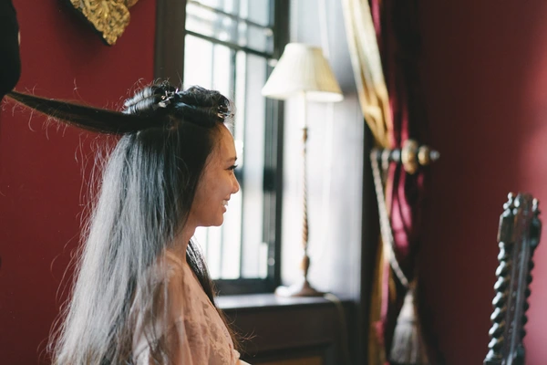 Bride in profile with a long white veil and floral hair piece, natural light flooding her face