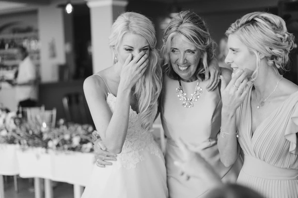Bride laughing with friends at the reception — natural joy and togetherness. Black-and-white.