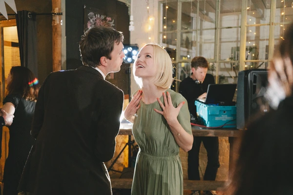 Man and woman dancing at the reception, smiling at each other — warm lighting, glass windows