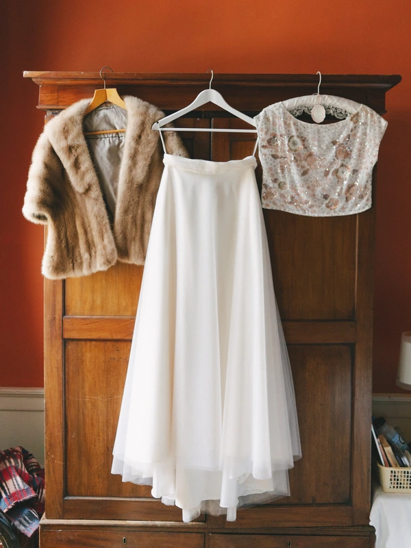 Bridal gown and accessories on an antique wooden wardrobe in front of a terracotta wall