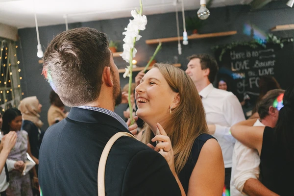 A couple dances at the reception — woman with a radiant smile, white flower garlands above