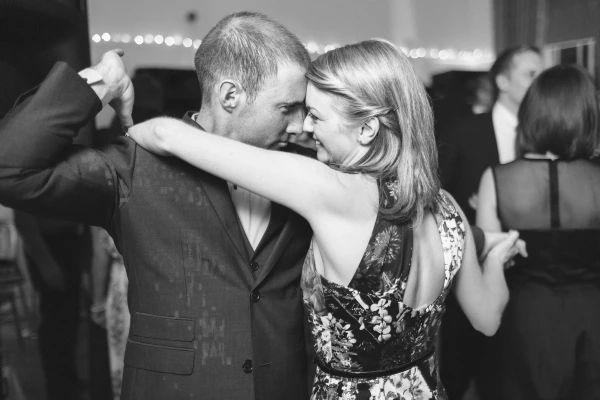 Three women make exaggerated, playful expressions while dancing together at the wedding reception. Candid and fun documentary wedding photograph.