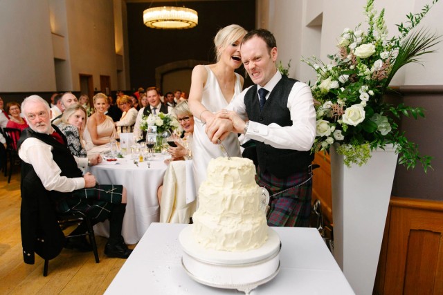 Bride and groom are cutting the cake at their Edinburgh Castle wedding celebration