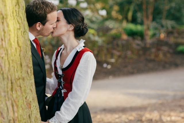 Couple sharing a kiss beside a moss-covered tree, outdoor setting in the Royal Botanic Garden Edinburgh