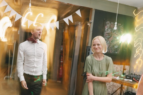 Boy in white shirt and girl in green enjoy the party amid neon lighting — smiling faces