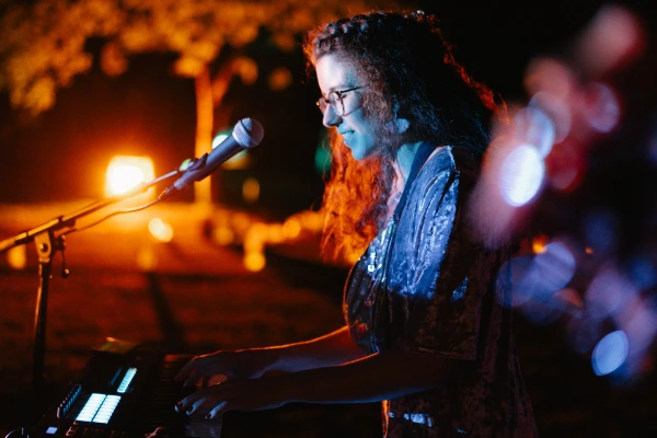 Female singer performs passionately at wedding event — microphone, orange stage lighting, intimate performance, live entertainment.