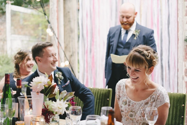 Bride laughing at the speeches at the wedding table, groom and guests with cheerful faces