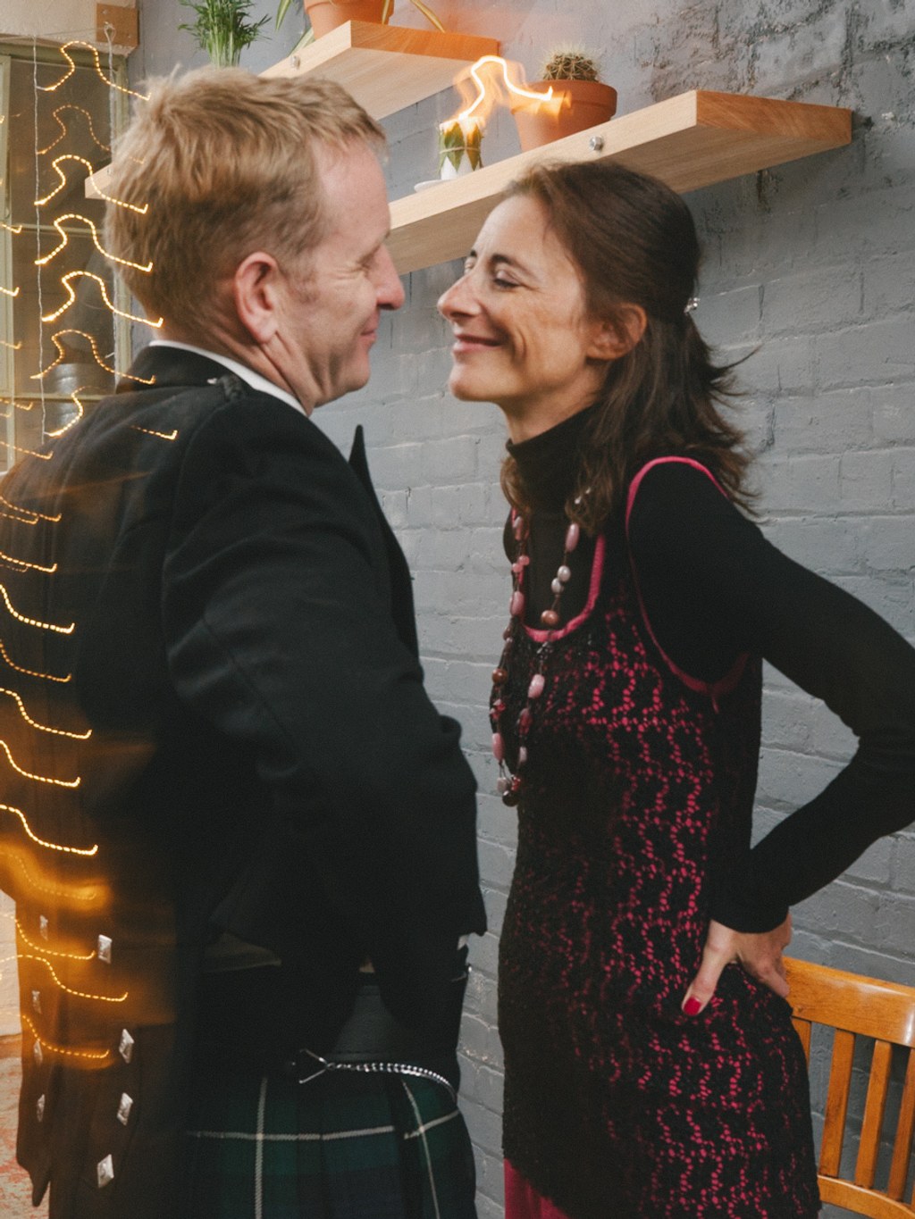 Man and woman smiling at each other in a modern loft — gold LED decoration, grey brick wall