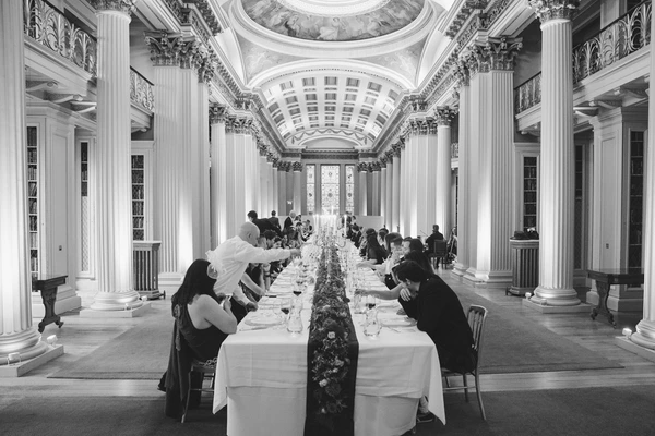 Wedding dinner table in a neoclassical hall — Corinthian columns, decorated dome, guests seated