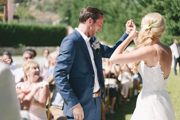 Bride and groom first dance in the garden — white wedding gown, blonde braided crown, groom smiles