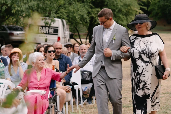 Groom arriving at the wedding ceremony with his mother. Emotional moment of family arrival at the wedding, captured in documentary style.
