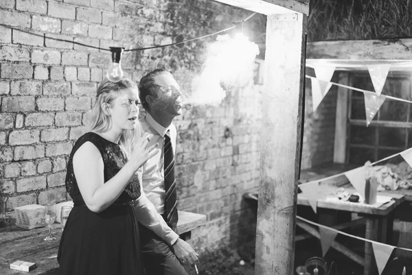 Woman and man talking in an industrial brick courtyard — vintage bulb and bunting decoration