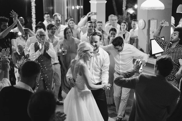 Bride and groom dance on the floor as guests celebrate around them at the evening reception