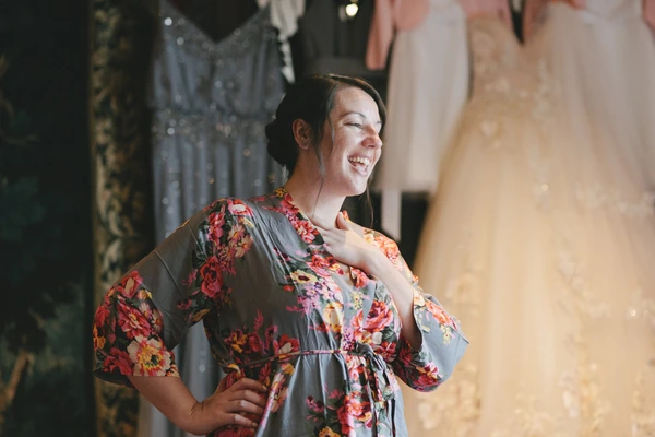 Smiling guest in floral dress at the wedding celebration, warm light, century-old stone walls