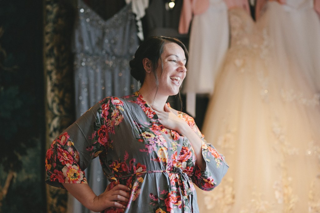Smiling guest in floral dress at the wedding celebration, warm light, century-old stone walls
