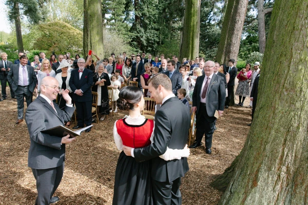 The newlyweds sharing their first kiss as a married couple under the trees at the Royal Botanic Garden Edinburgh ceremony. Romantic documentary moment.