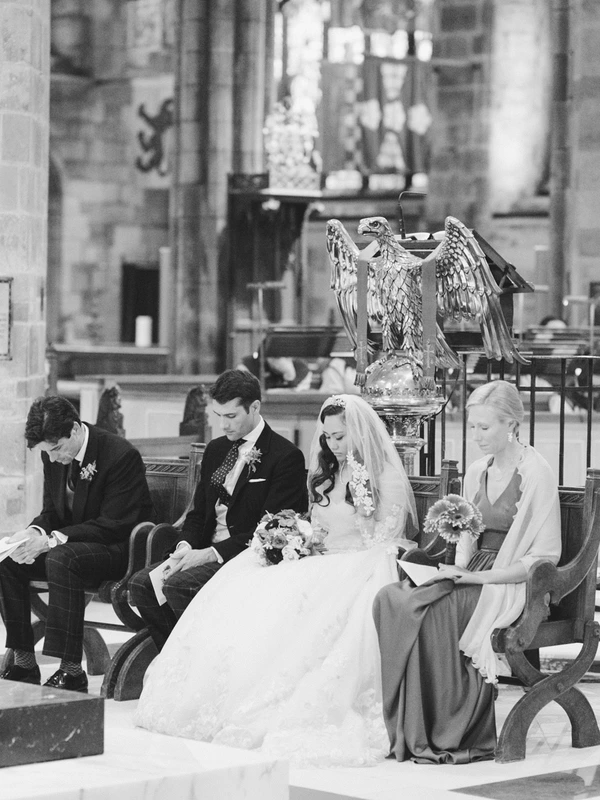 Bride and groom in the church pew, family beside them — eagle sculpture, classical architecture