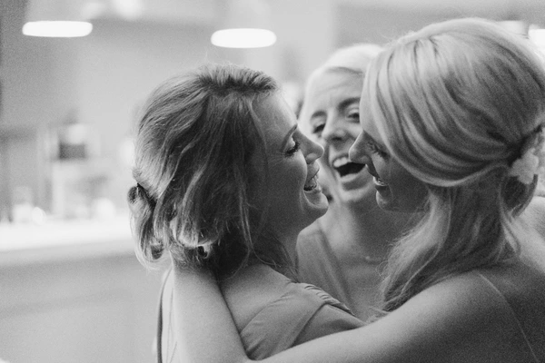 Bride and wedding guests in cheerful conversation — black-and-white close-up, smiling faces indoors