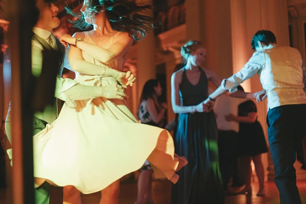 Bride's tulle veil flies as she dances with the groom — warm gold and cool teal light play on them