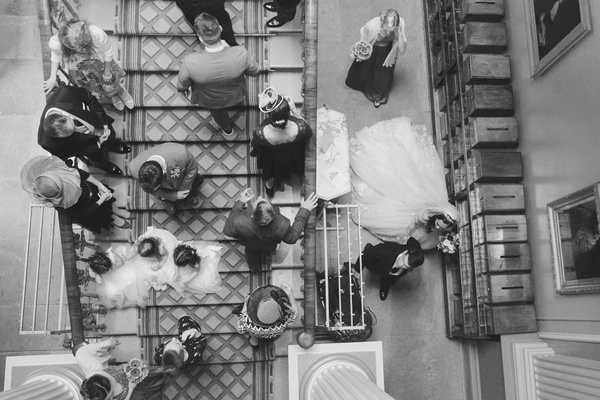 Aerial view of the wedding — bride's white gown and groom's black suit visible, guests around
