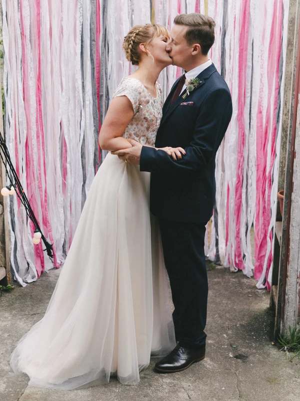 First kiss of bride and groom before the ribbon decoration — romantic cheering moment