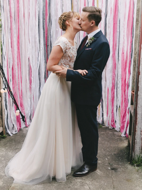 First kiss of bride and groom before the ribbon decoration — romantic cheering moment